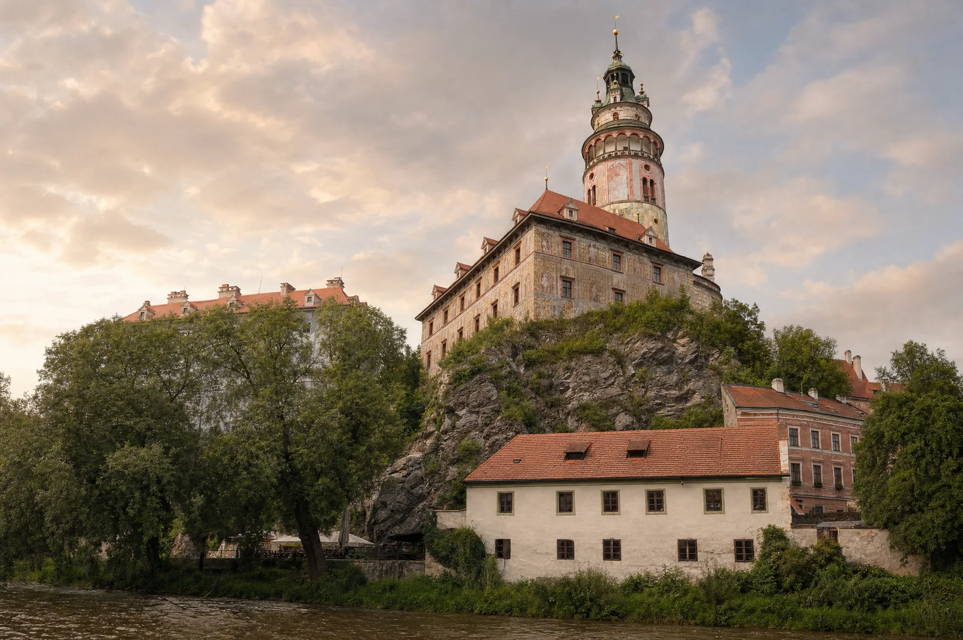Kulatá renesanční zámecká věž s malovanou výzdobou a měděnou bání na skále nad řekou