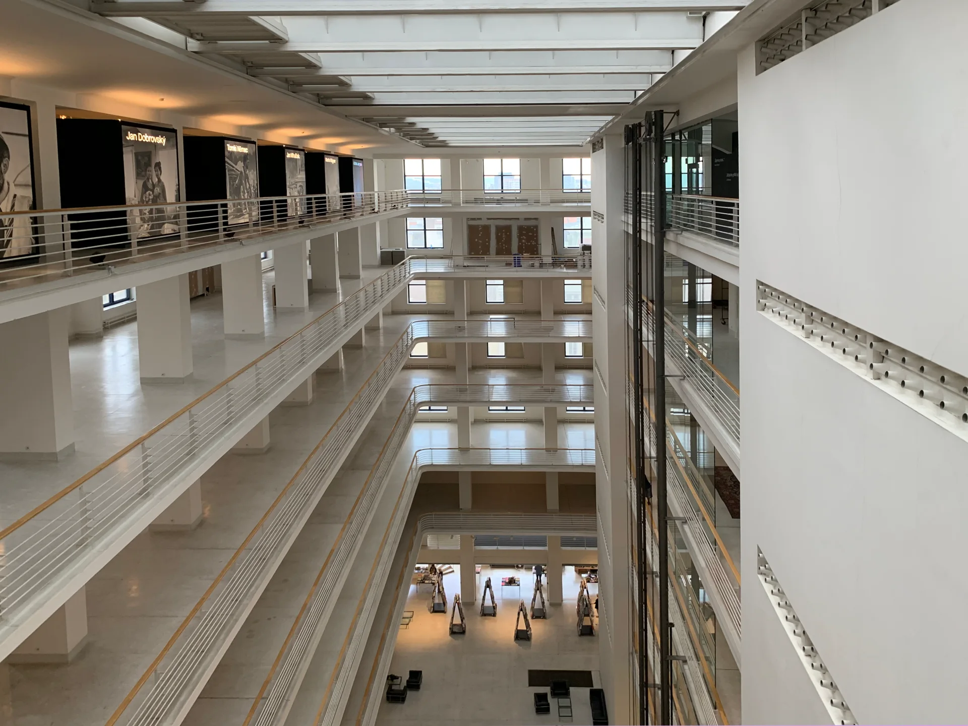 Prosklené atrium Veletržního paláce v Praze s bílými ochozy pater a funkcionalistickým interiérem
