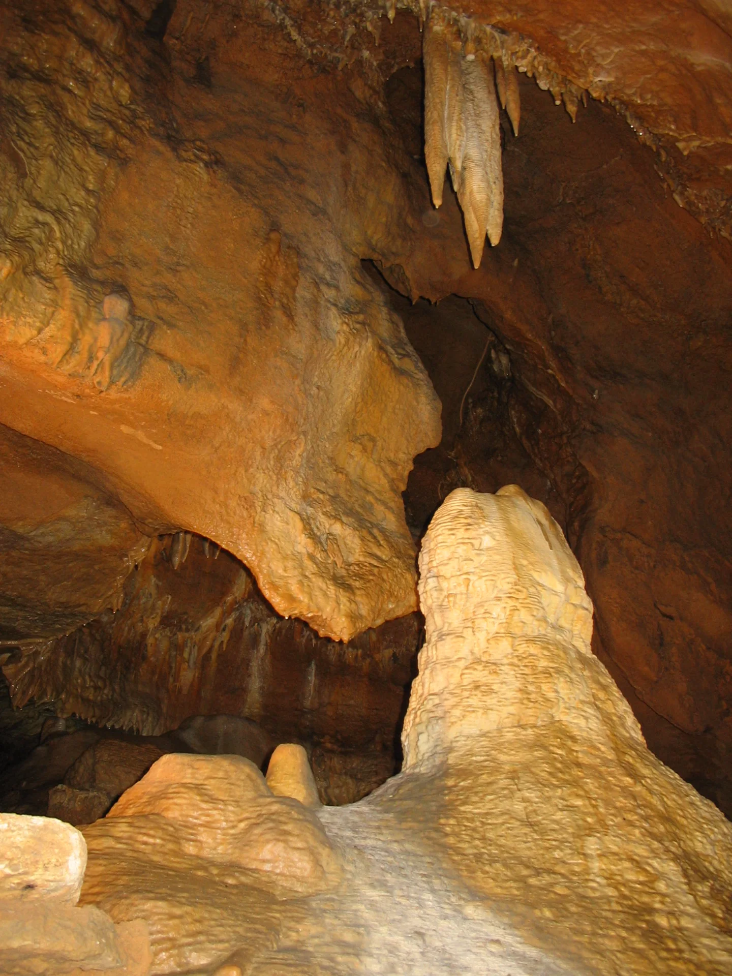 Mohutný stalagmit ve svahu jeskynní chodby