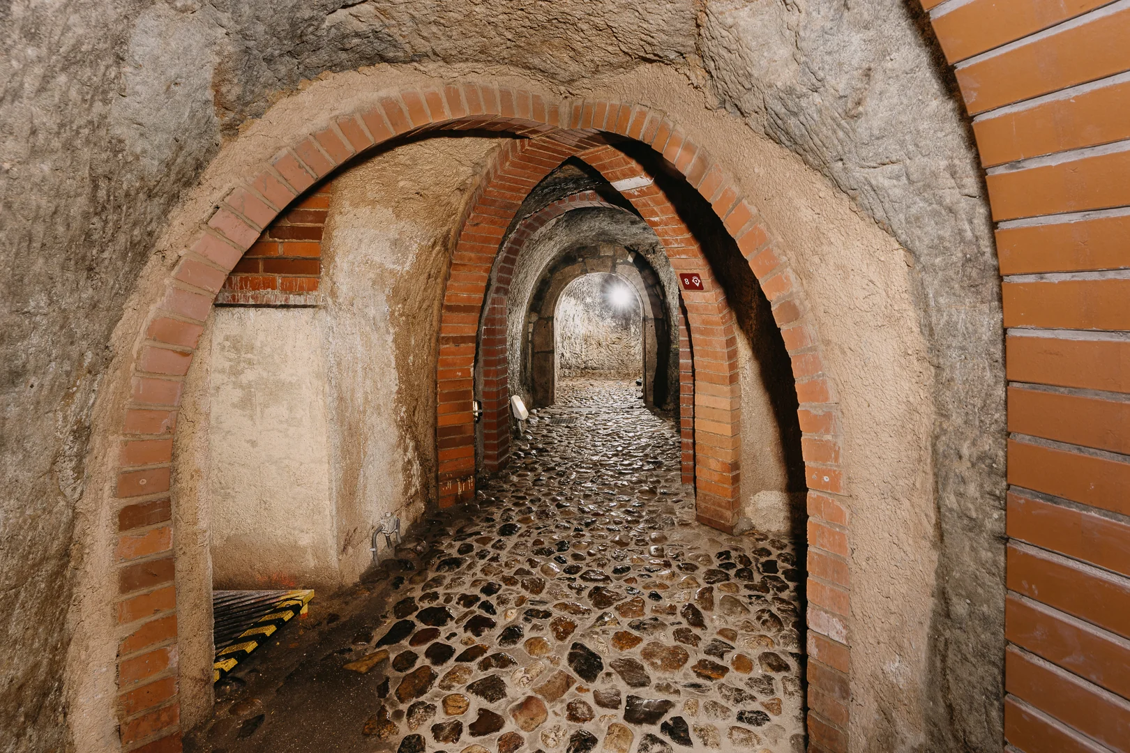 Cihlová klenba nad chodbou s kamennou dlažbou