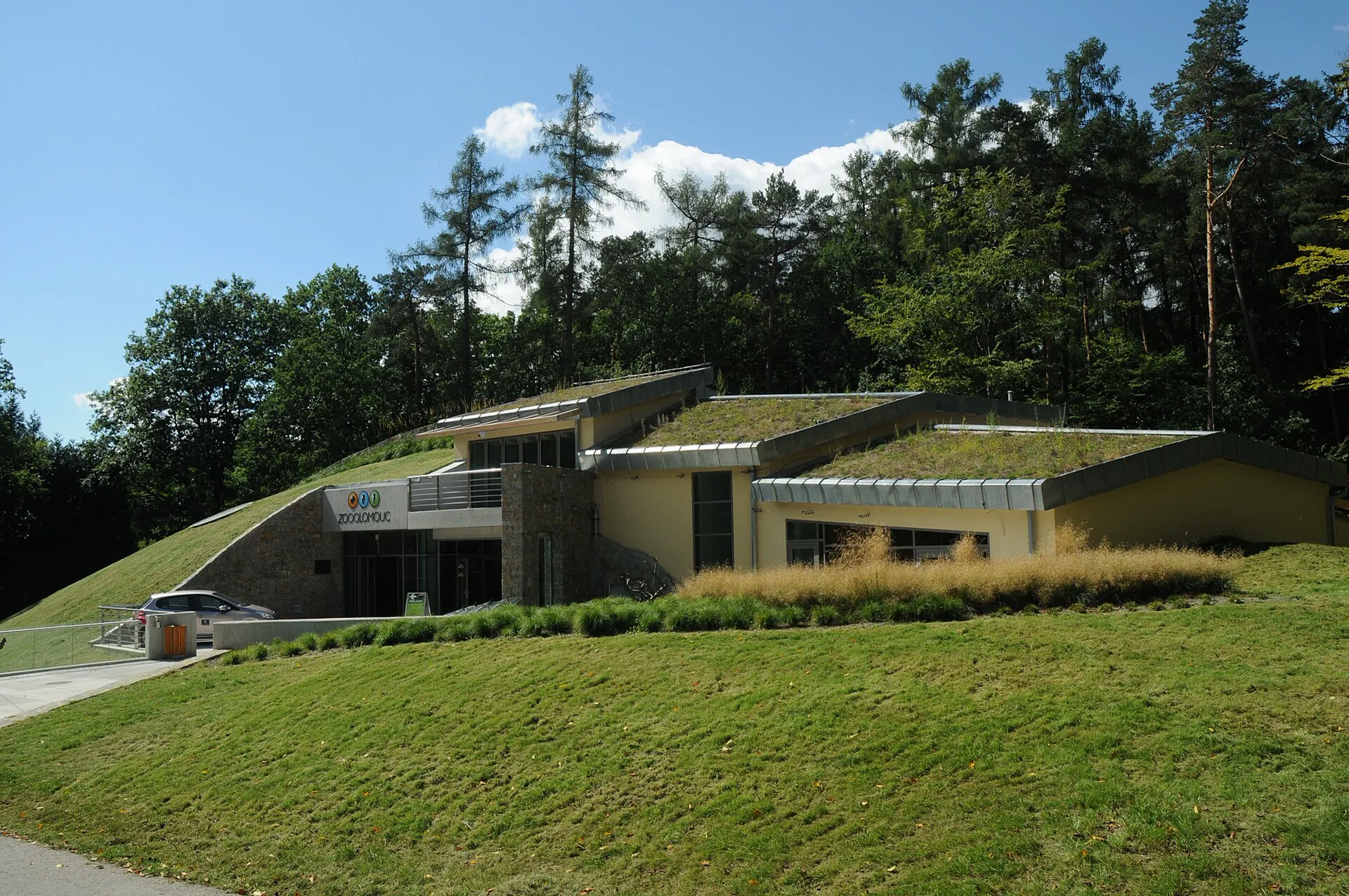 Moderní vstupní budova zoo se zelenou střechou v lese