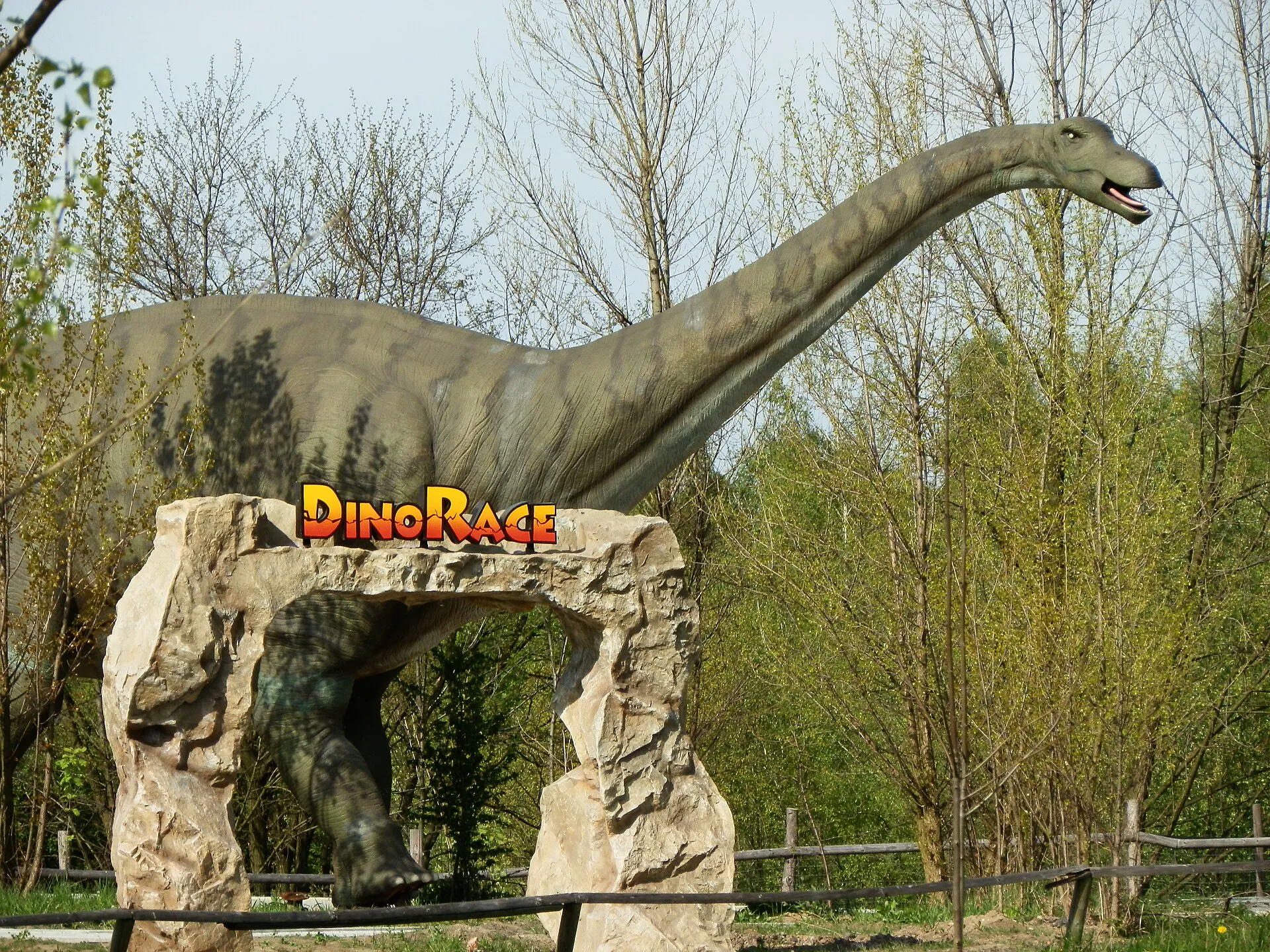 Model dinosaura nad kamennou branou s nápisem DinoRace