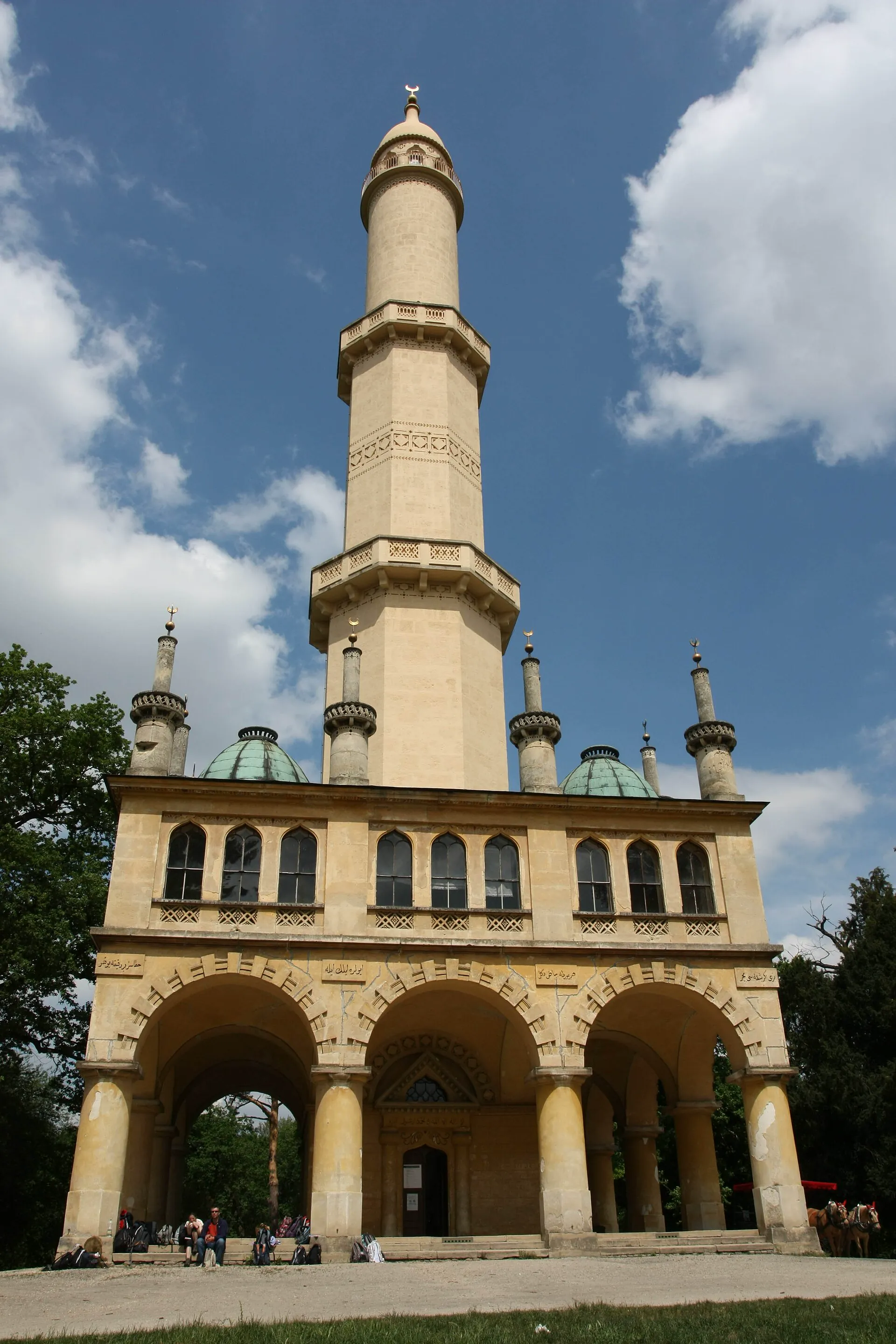 Minaret s arkádovým přízemím a štíhlou věží proti modré obloze