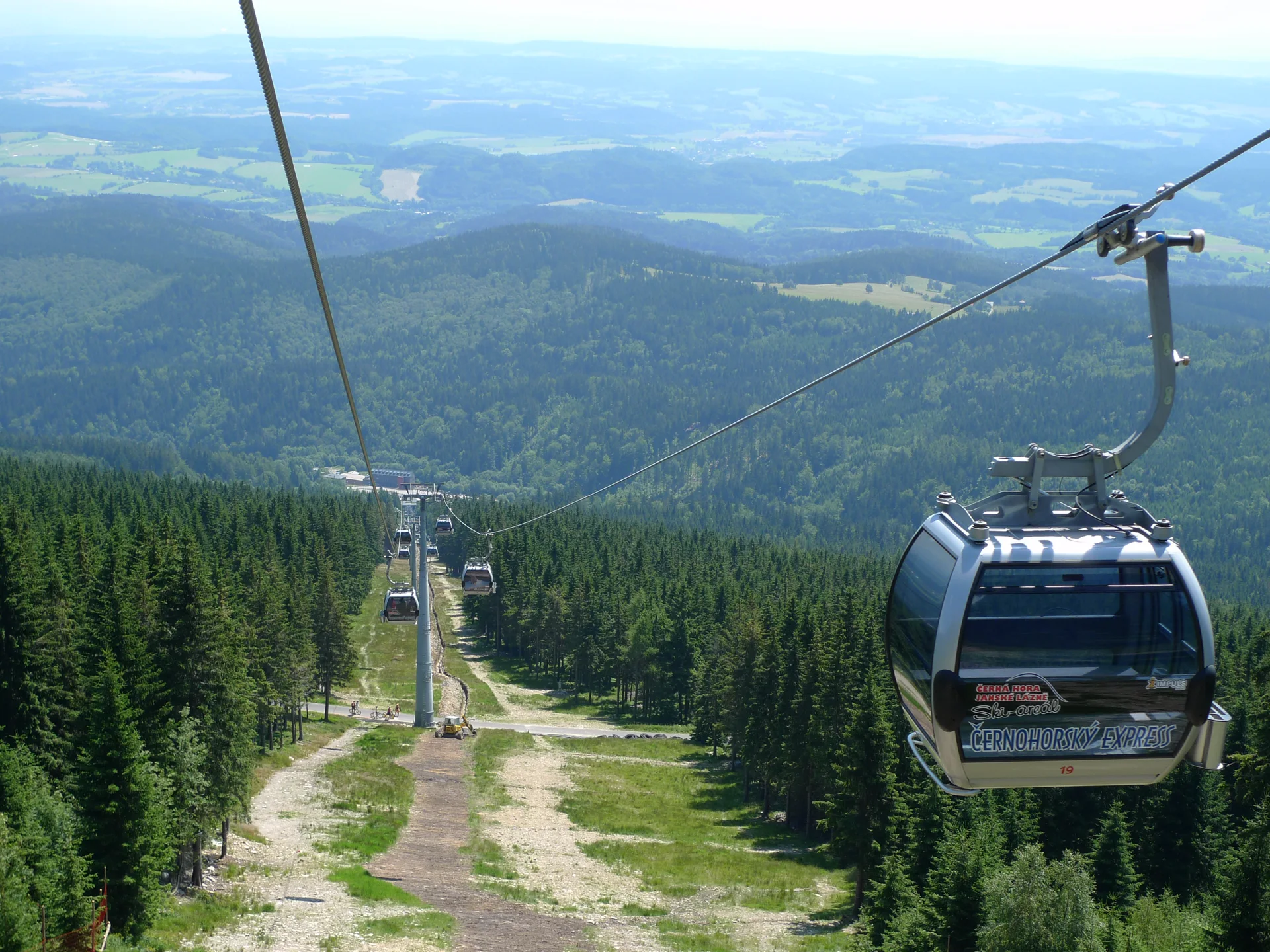 Kabinka lanovky Černohorský Express nad letním lesem