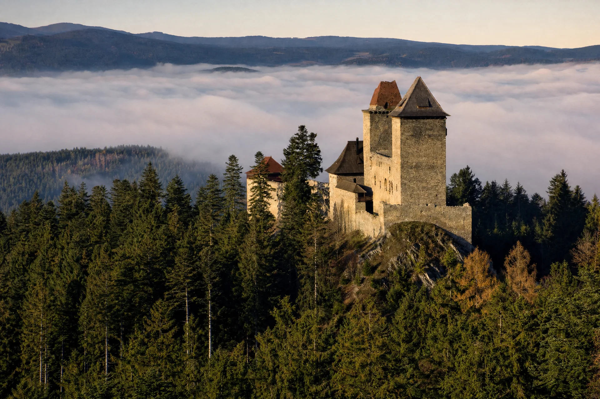 Hrad Kašperk na šumavském hřebeni nad mořem mlhy v podvečerním světle