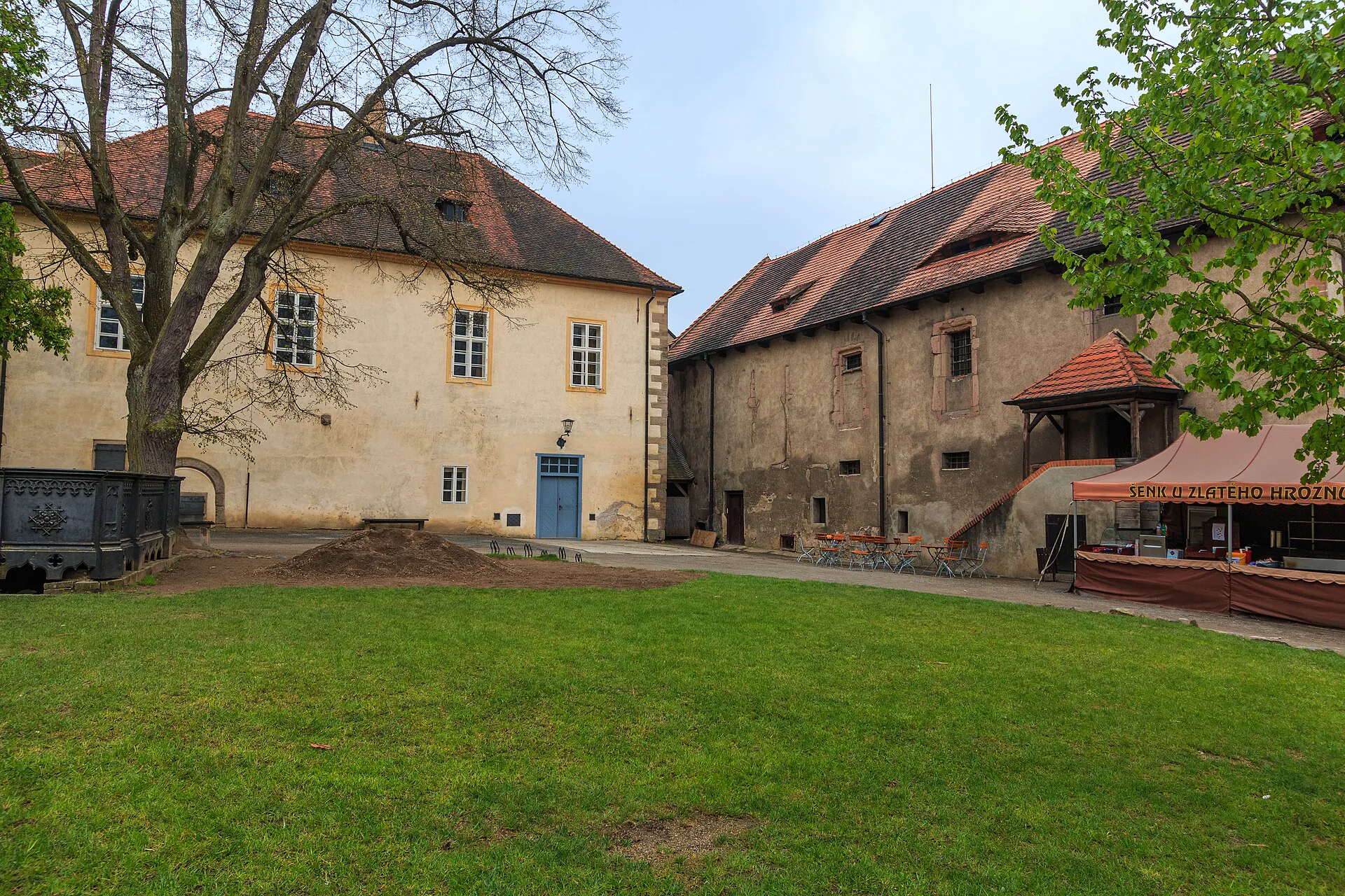 Vnitřní nádvoří hradu s gotickými budovami a travnatou plochou