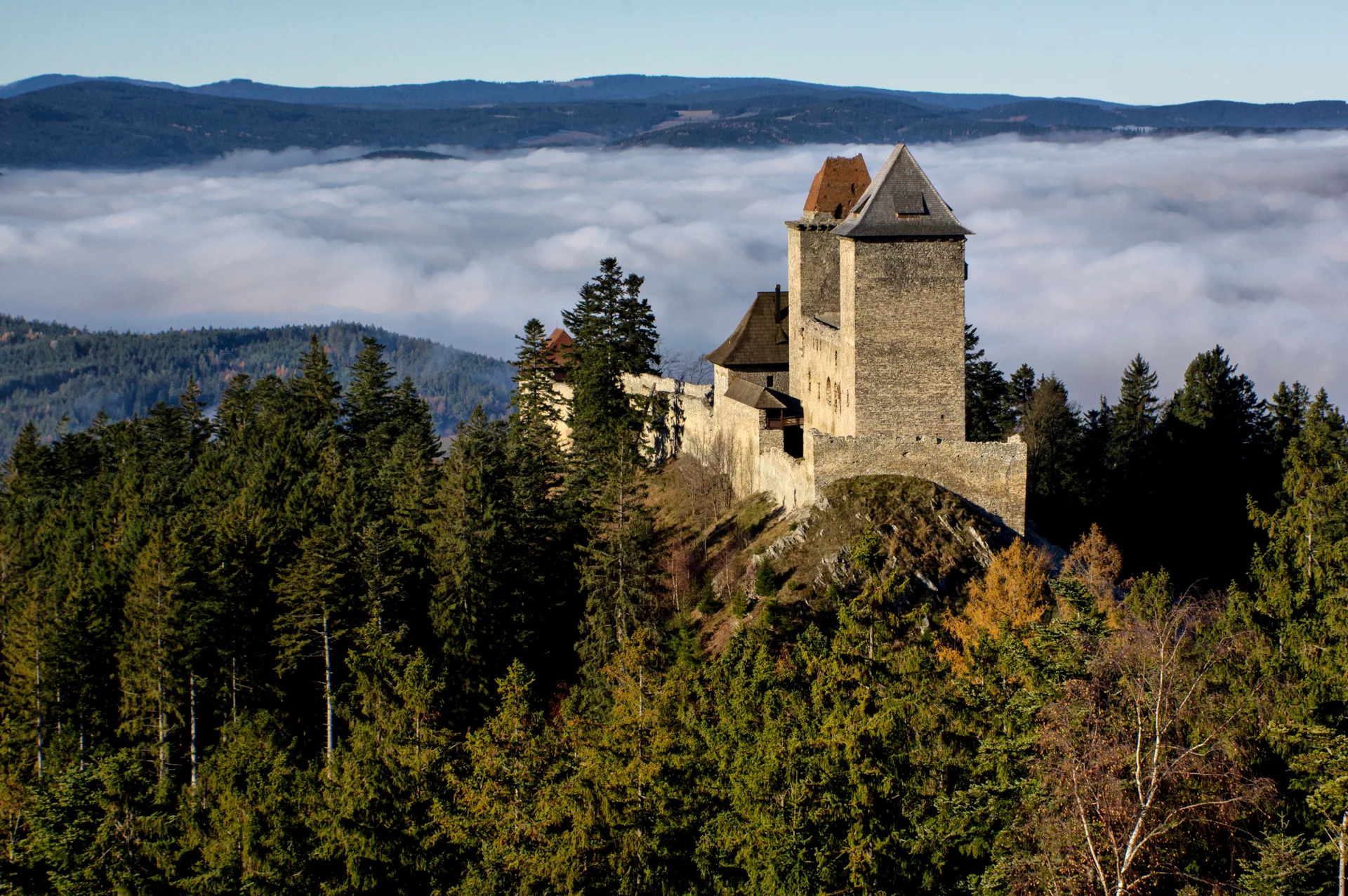Hrad Kašperk se dvěma věžemi nad podzimním šumavským lesem