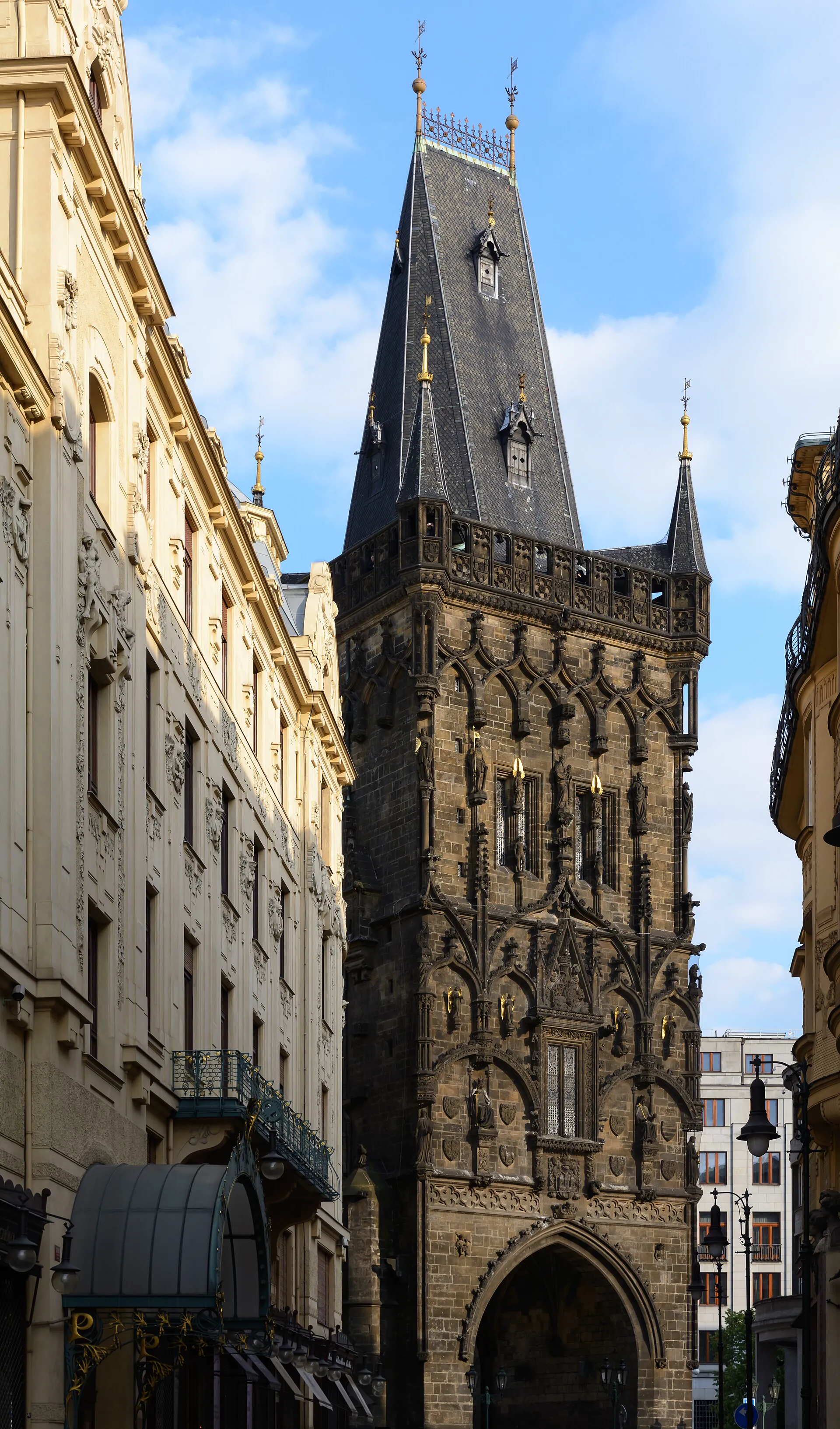 Detail zdobeného kamenného průčelí a špičaté střechy věže