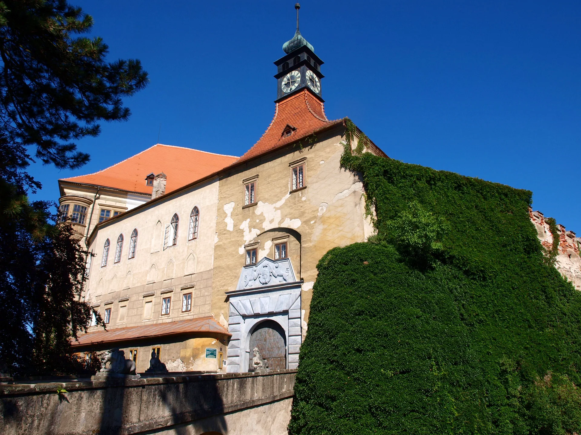 Zámecké průčelí s renesančním portálem a věží s hodinami