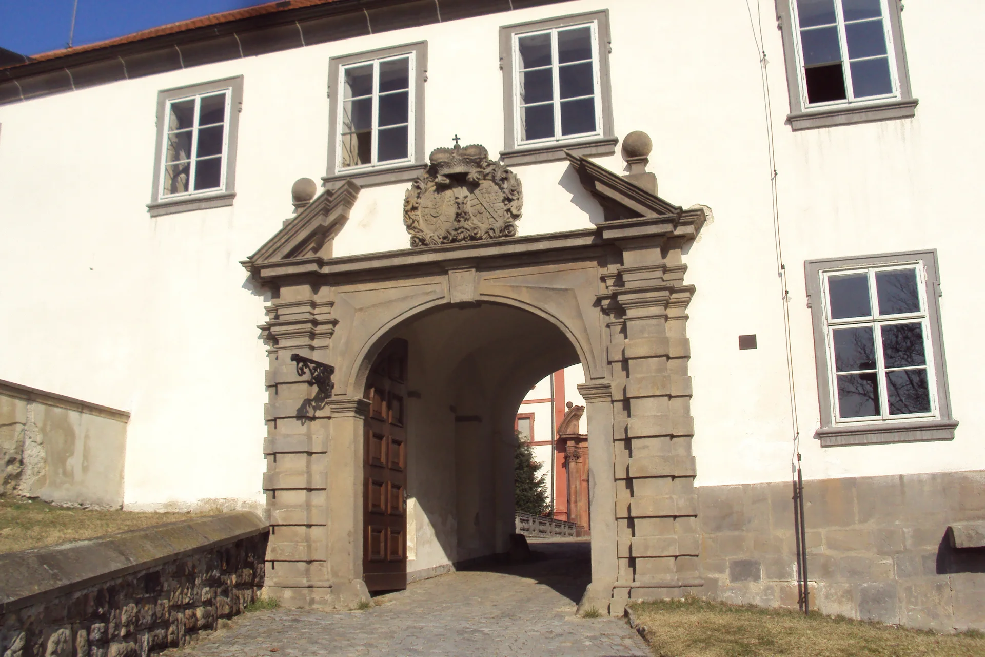 Kamenný vjezdový portál zámku Zákupy s erbem nad průjezdním obloukem