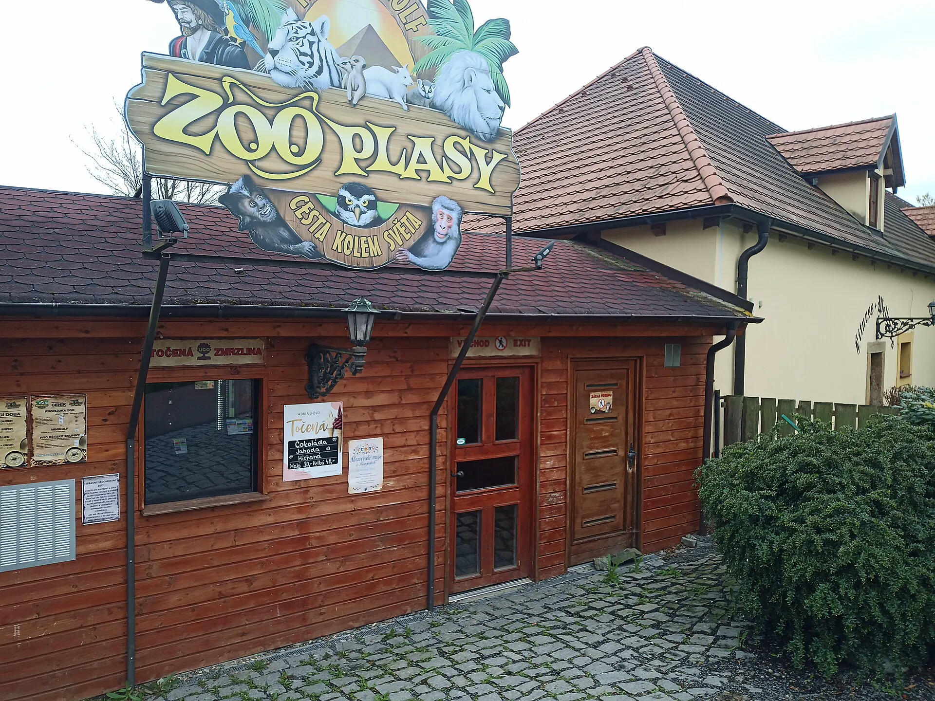 Dřevěná vstupní budova zoo s vyřezávanou cedulí Zoo Plasy