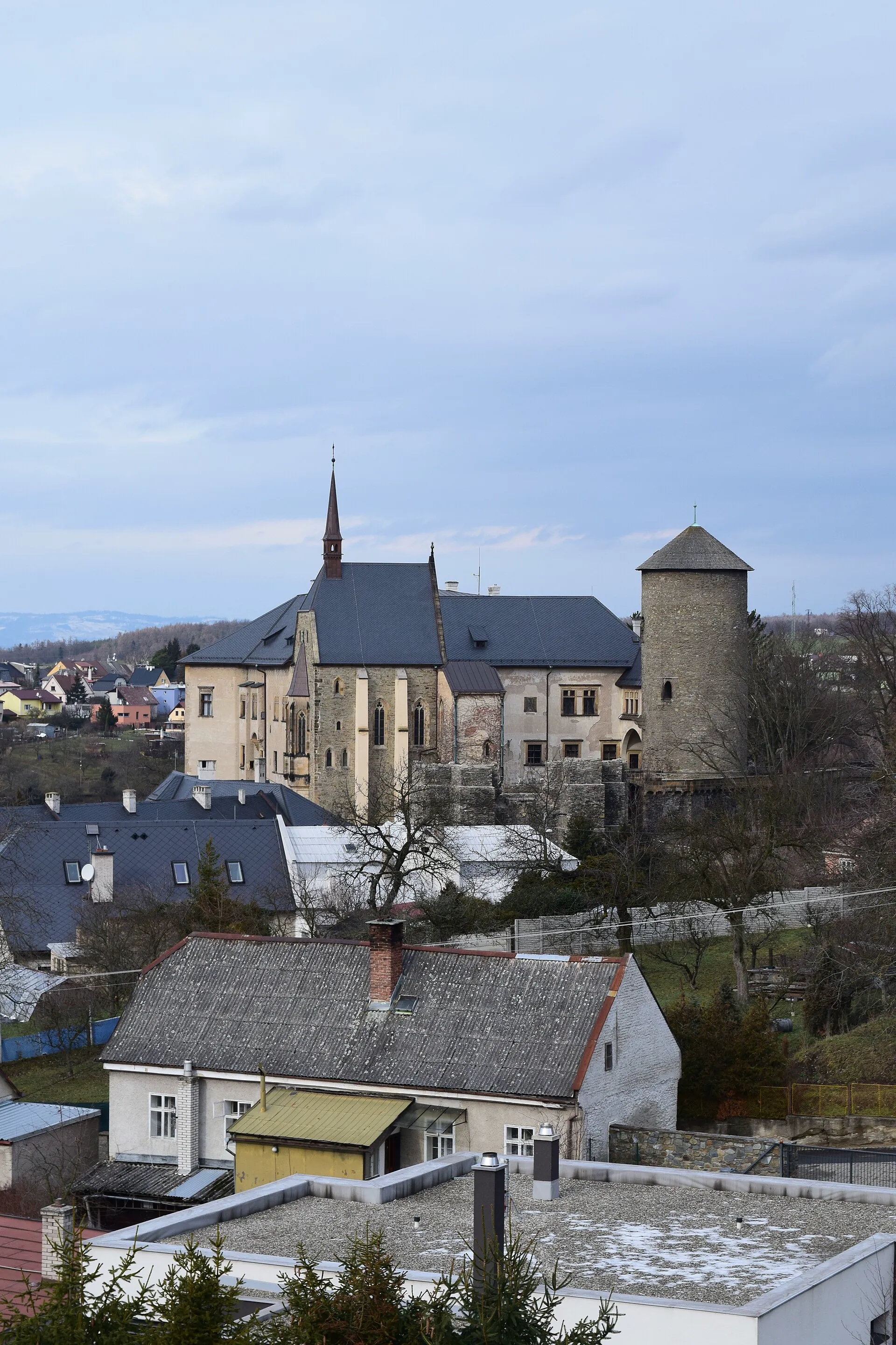 Hrad s věží a kostelem nad střechami města