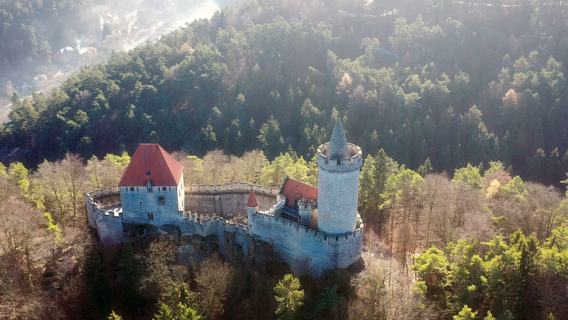 Letecký pohled na hrad Kokořín nad zalesněným Kokořínským dolem