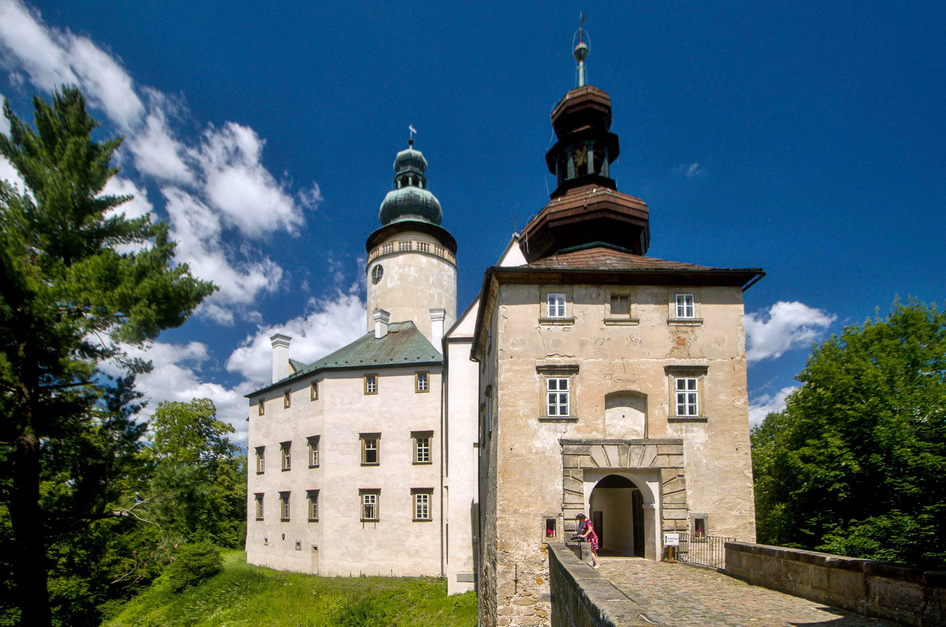Zámek Lemberk zvenku, bílé průčelí se dvěma věžemi a vstupním portálem nad svahem