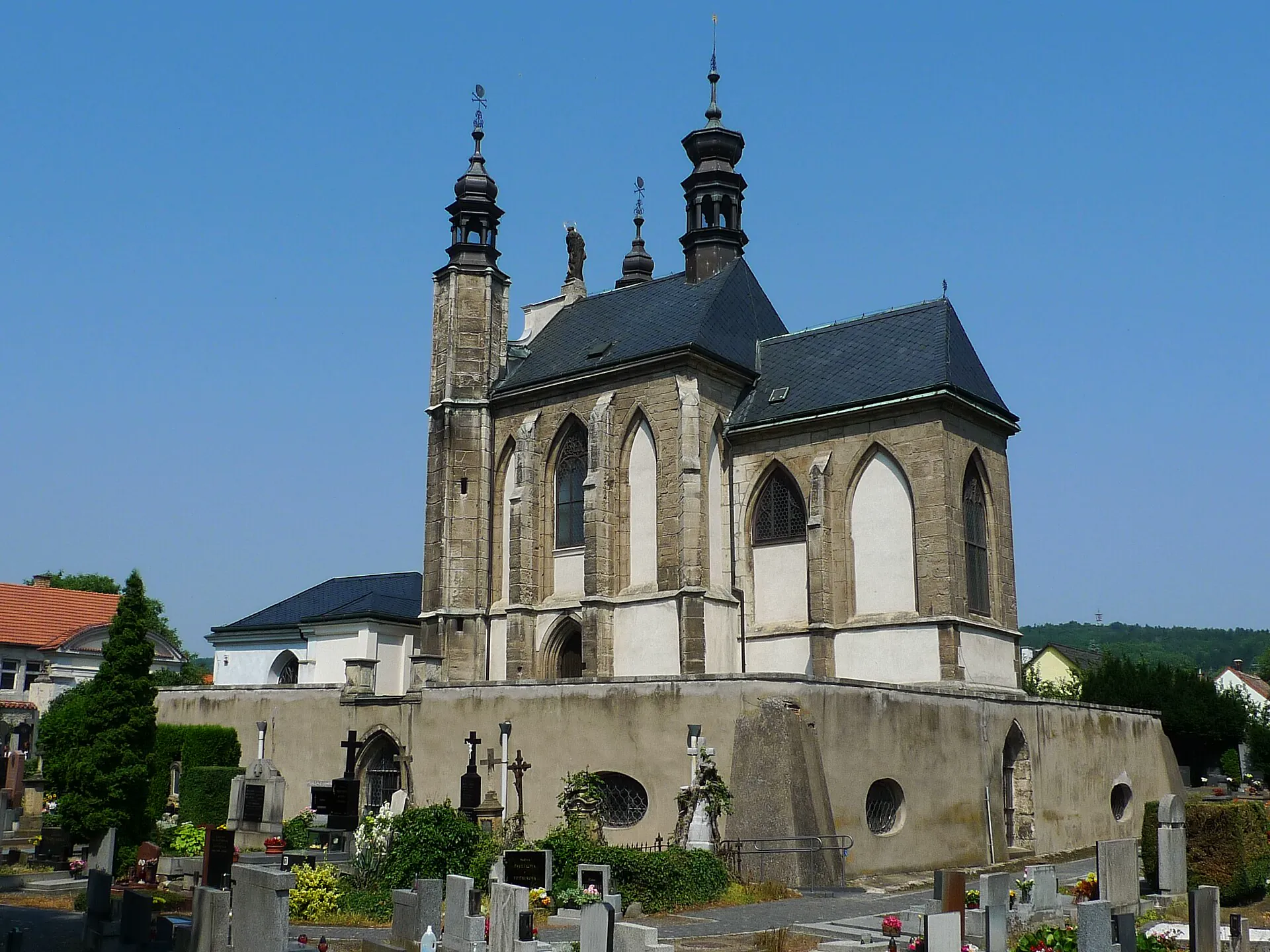 Gotický kostel Všech svatých s kostnicí a dvěma věžemi nad hřbitovem