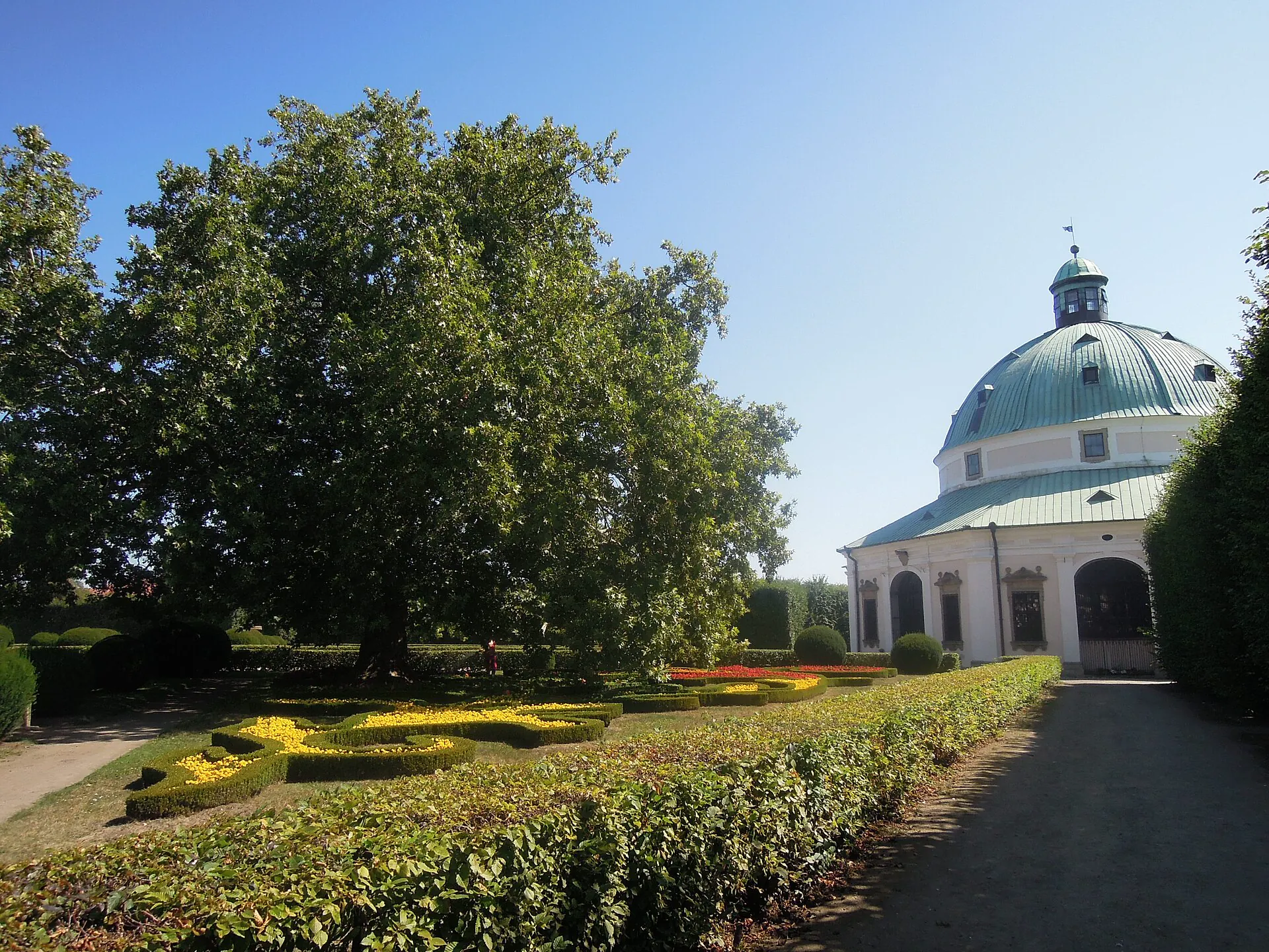 Rotunda Květné zahrady obklopená stromy za slunečného dne