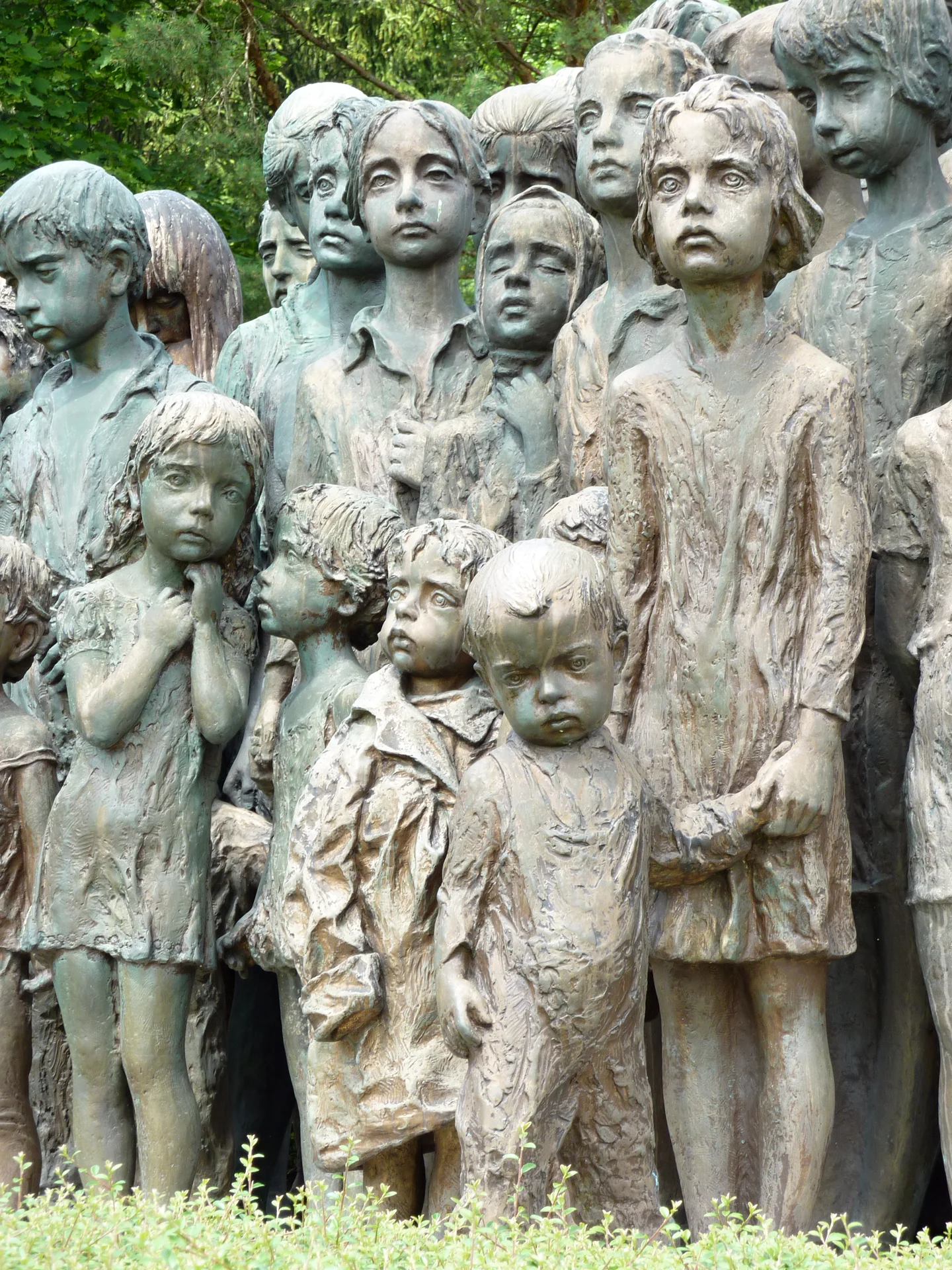 Detail tváří dětí ze sousoší Marie Uchytilové, pohled zblízka na bronzové postavy