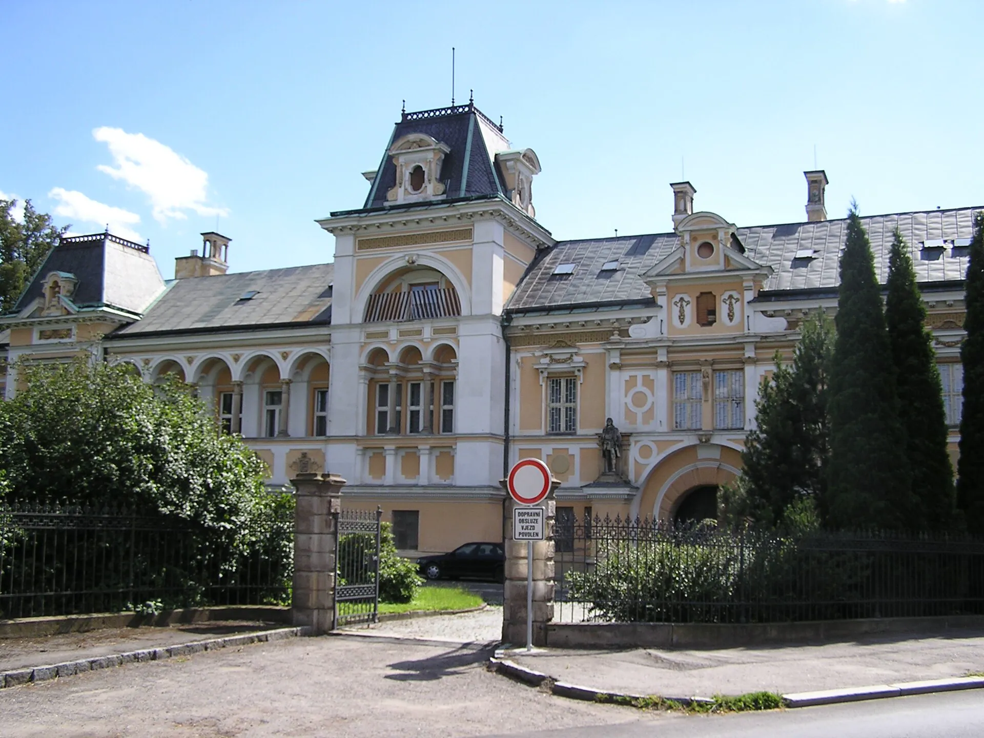 Průčelí zámku se žlutou fasádou a vstupní branou