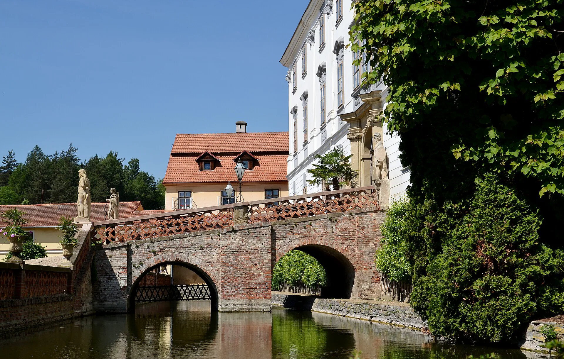 Kamenný můstek se sochami přes vodní příkop u zámku
