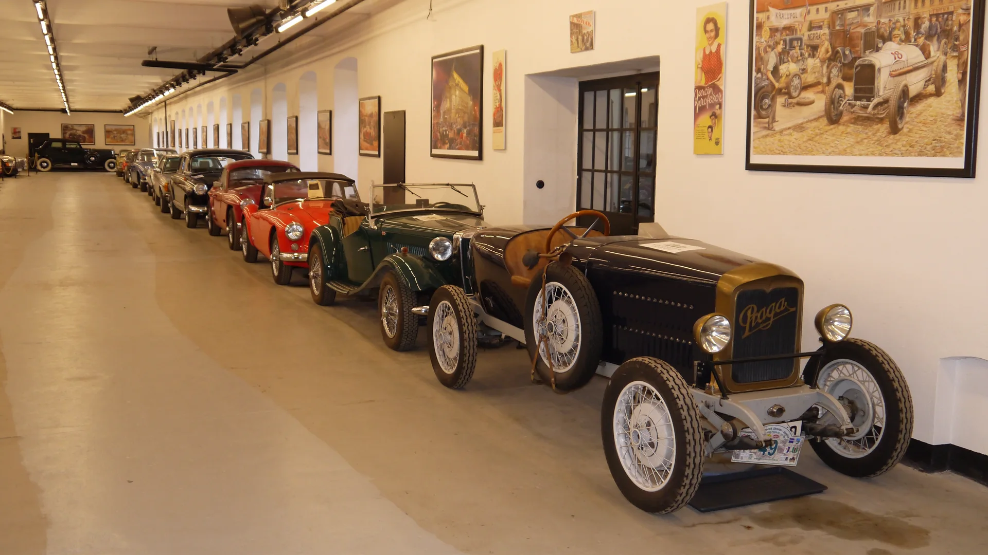 Řada historických automobilů vystavených v dlouhé hale muzea starých strojů a technologií