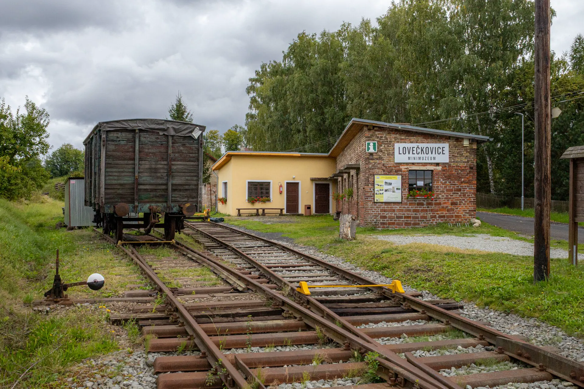 Celkový pohled na areál minimuzea s kolejemi a historickým nákladním vagonem
