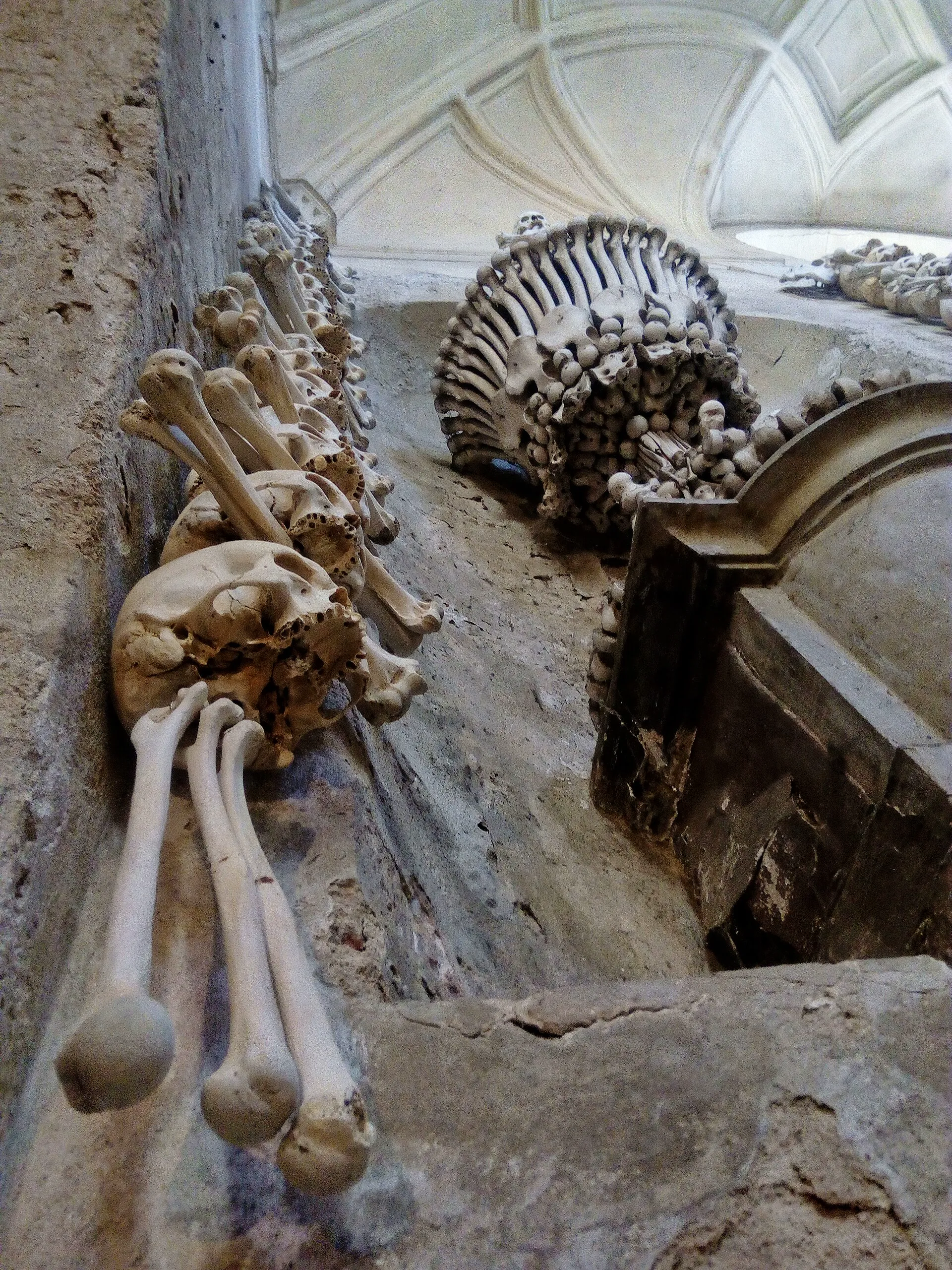 Výzdoba stěn z lidských kostí a lebek s pyramidou v pozadí
