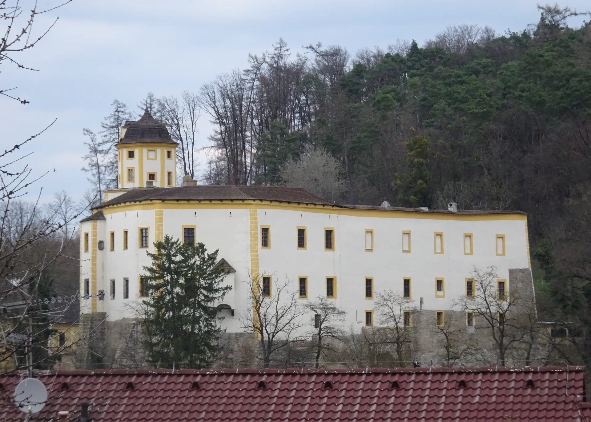 Hrad Malenovice na zalesněném ostrohu nad střechami Malenovic