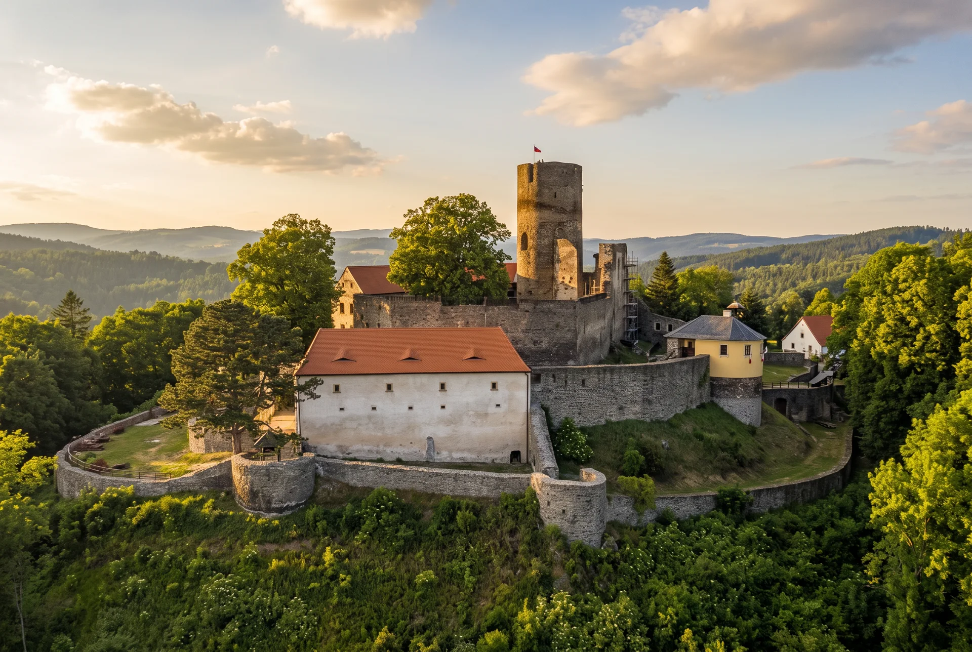 Hrad Svojanov s bílým palácem a kamennou věží na zalesněném kopci