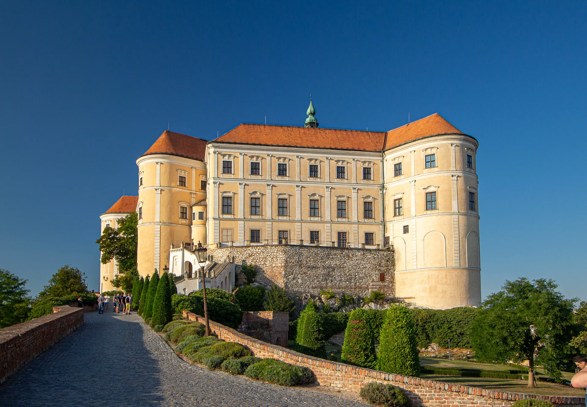 Zámek Mikulov v podvečerním slunci s upravenou zahradou před vstupem