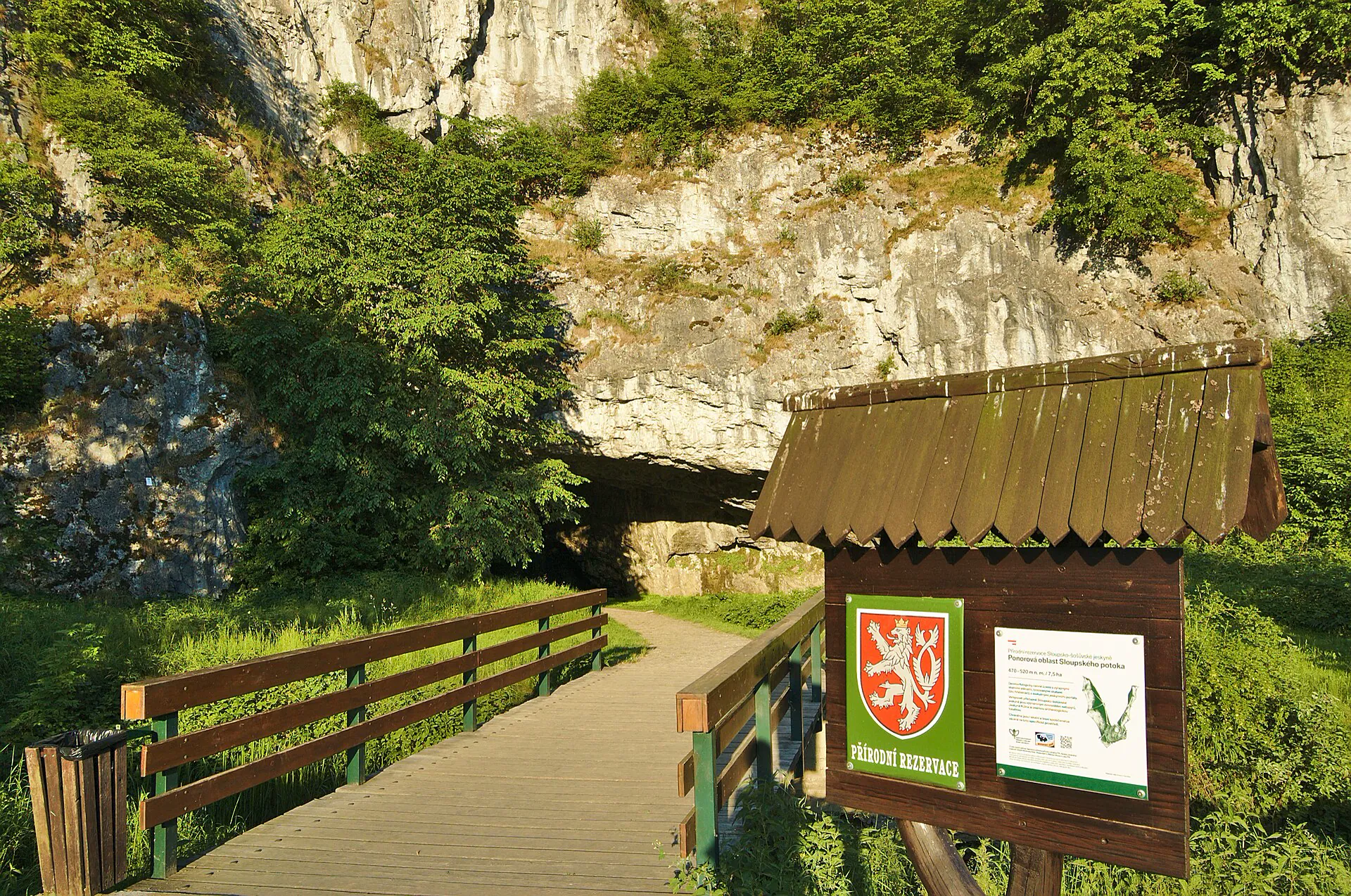 Vstup do jeskyní s dřevěnou lávkou u skalní stěny