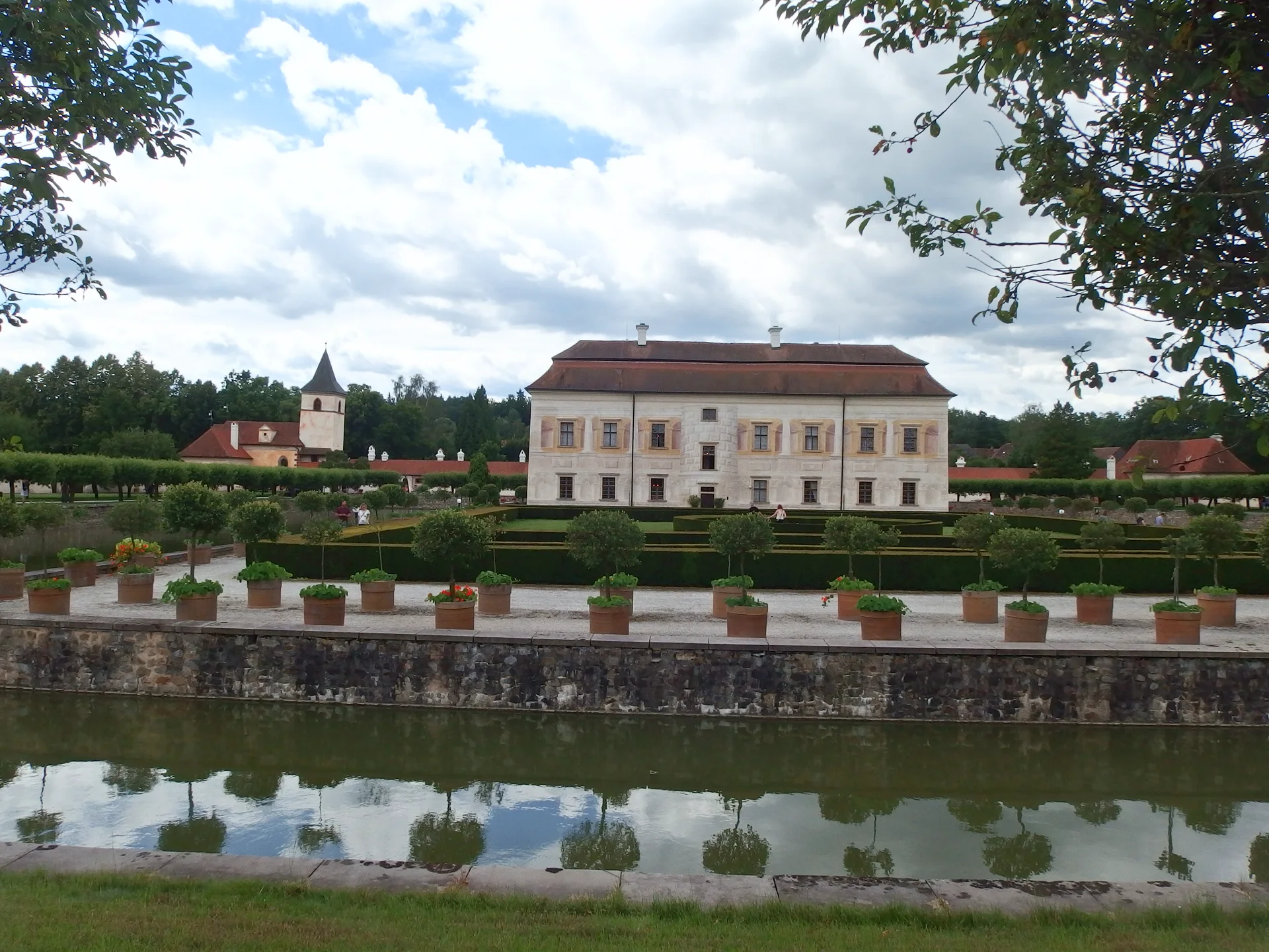 Pohled přes zahradu na vilu Kratochvíle a kostel Narození Panny Marie