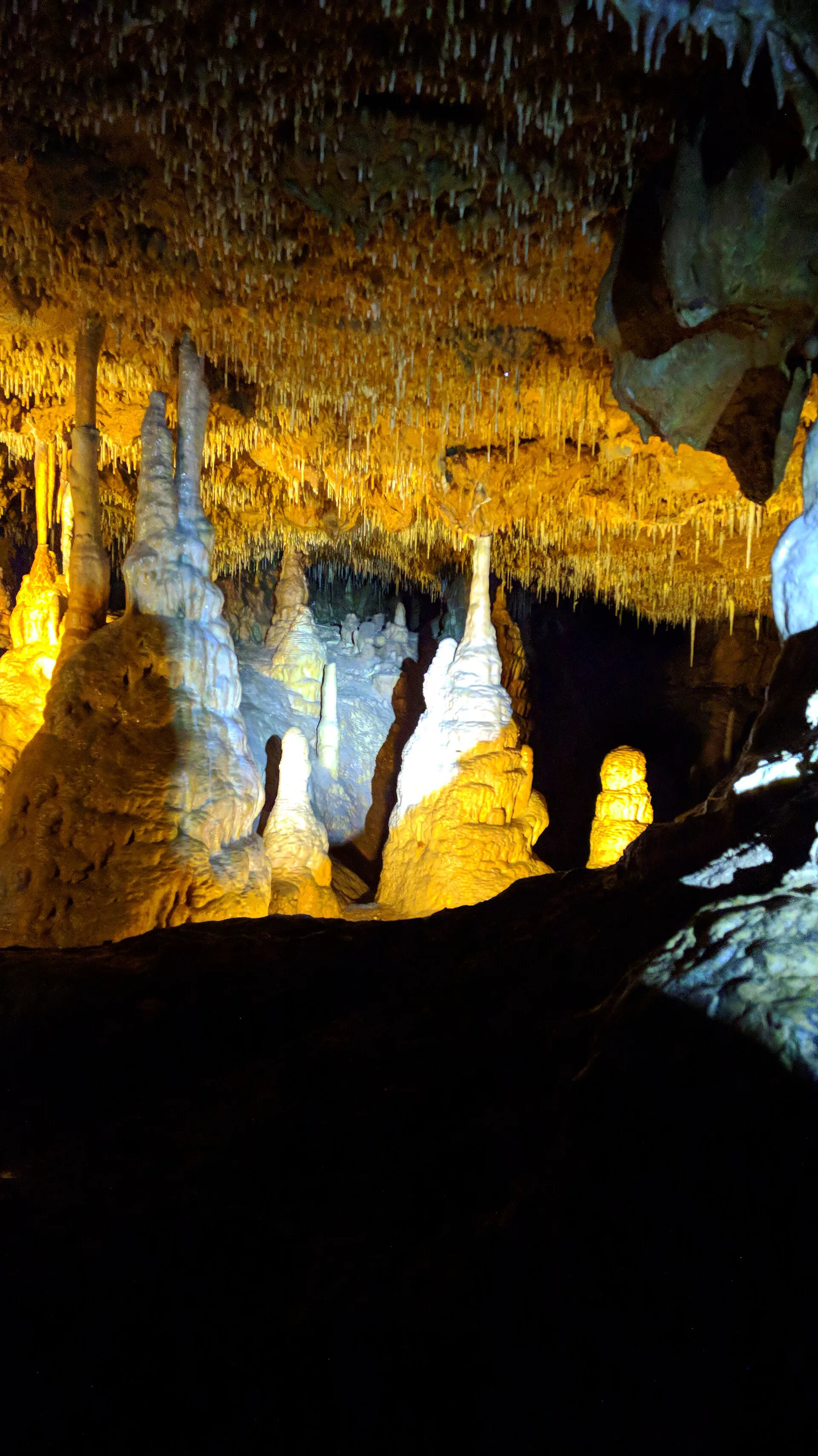 Zlatě nasvícené stalagmity a stalaktity v podzemním dómu