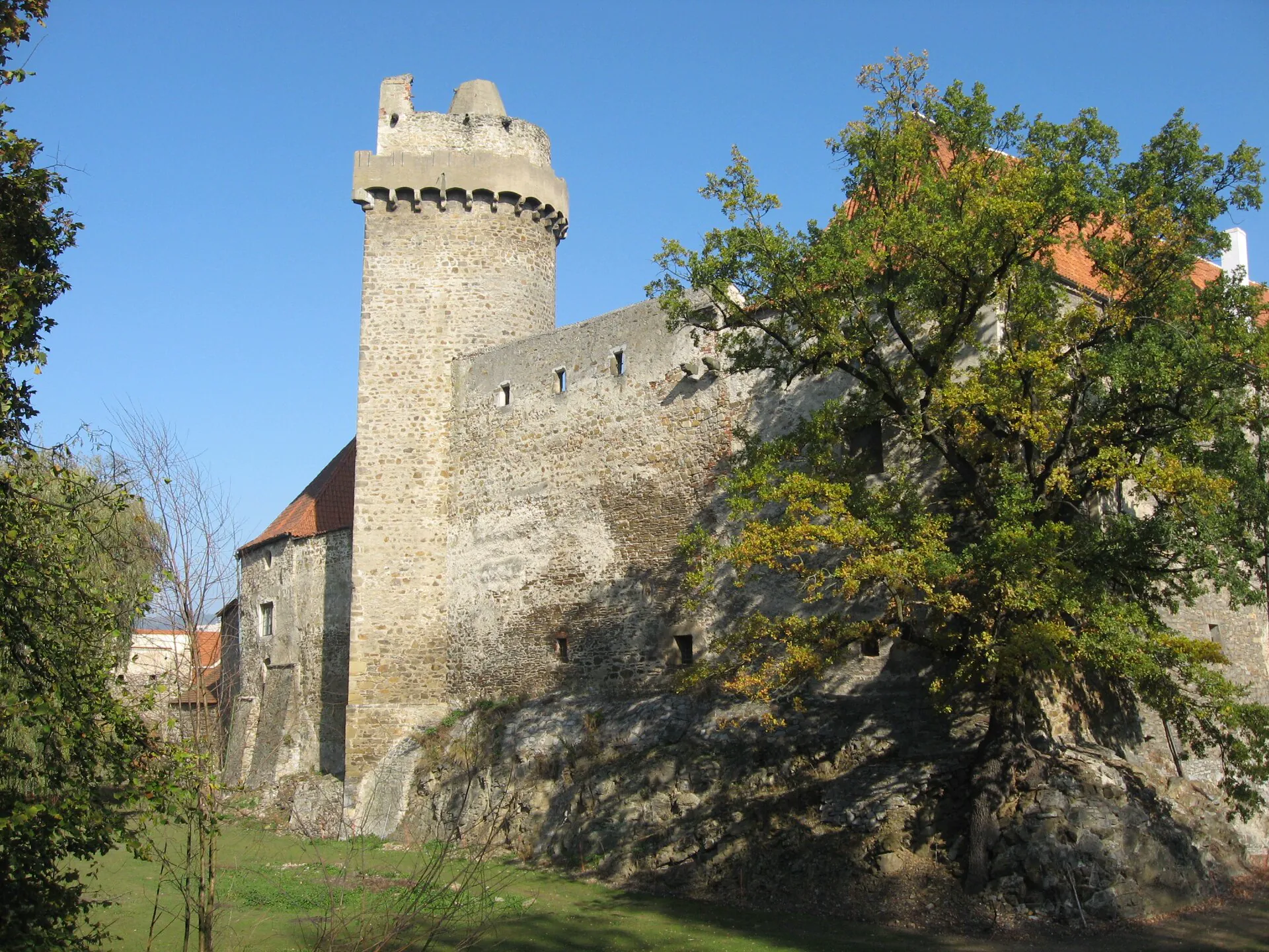 Věž Rumpál na skalnatém ostrohu obklopená podzimními stromy
