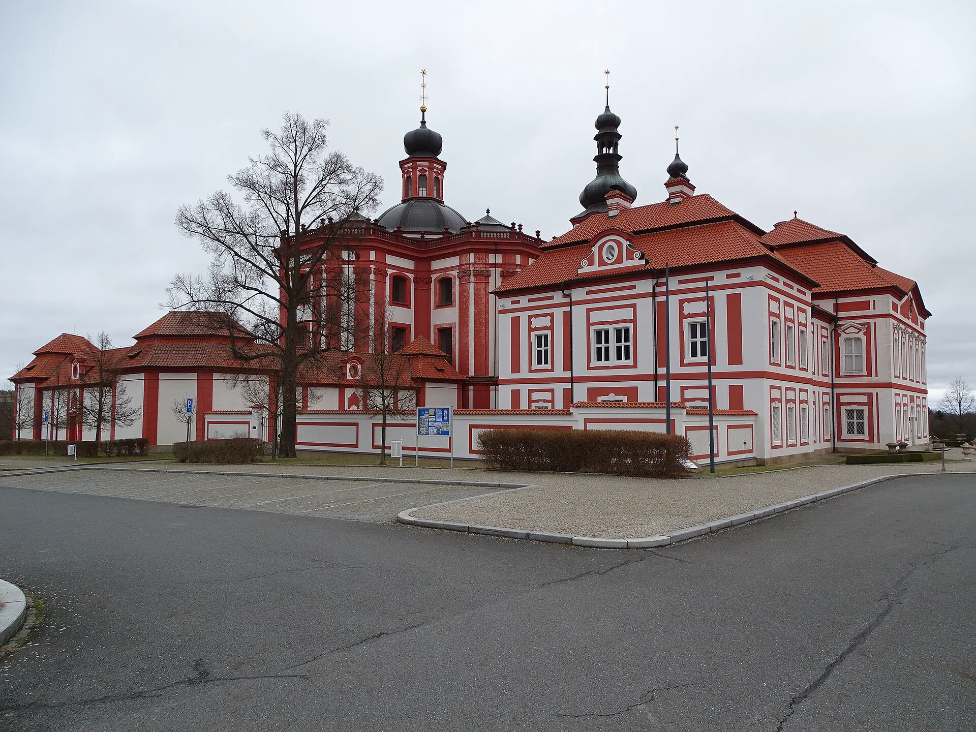 Červenobílé průčelí areálu s věžemi od parkoviště