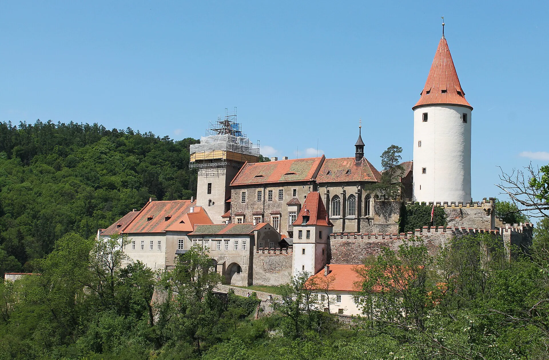 Hrad Křivoklát s mohutnou válcovou věží nad lesnatým údolím