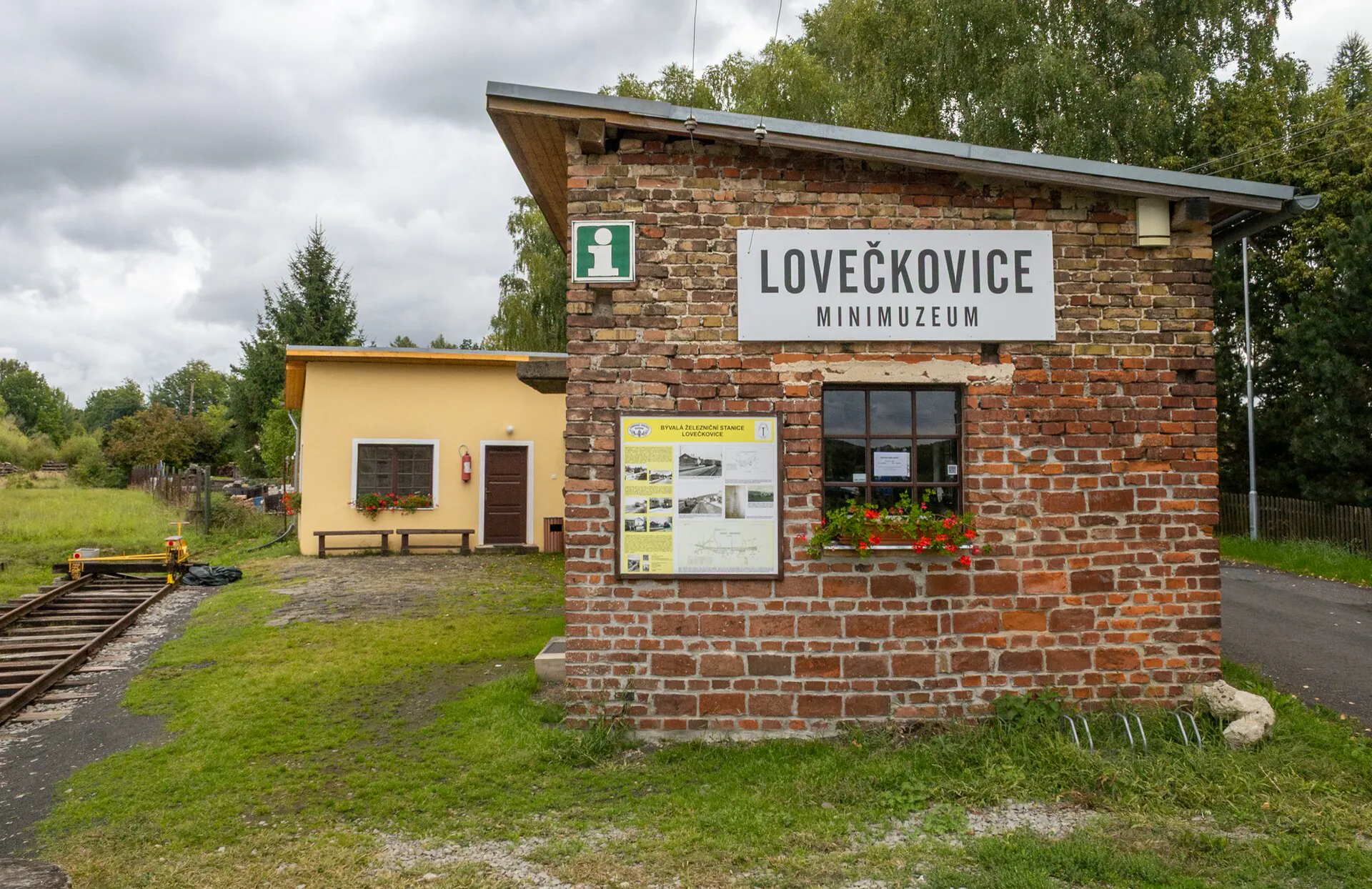 Cihlová drážní budova minimuzea s cedulí Lovečkovice minimuzeum a informační tabulí