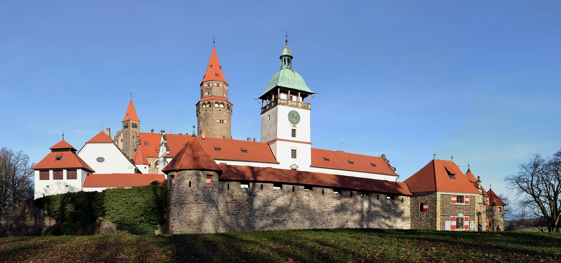 Panorama hradu Bouzov s věží hláskou nad zalesněným návrším