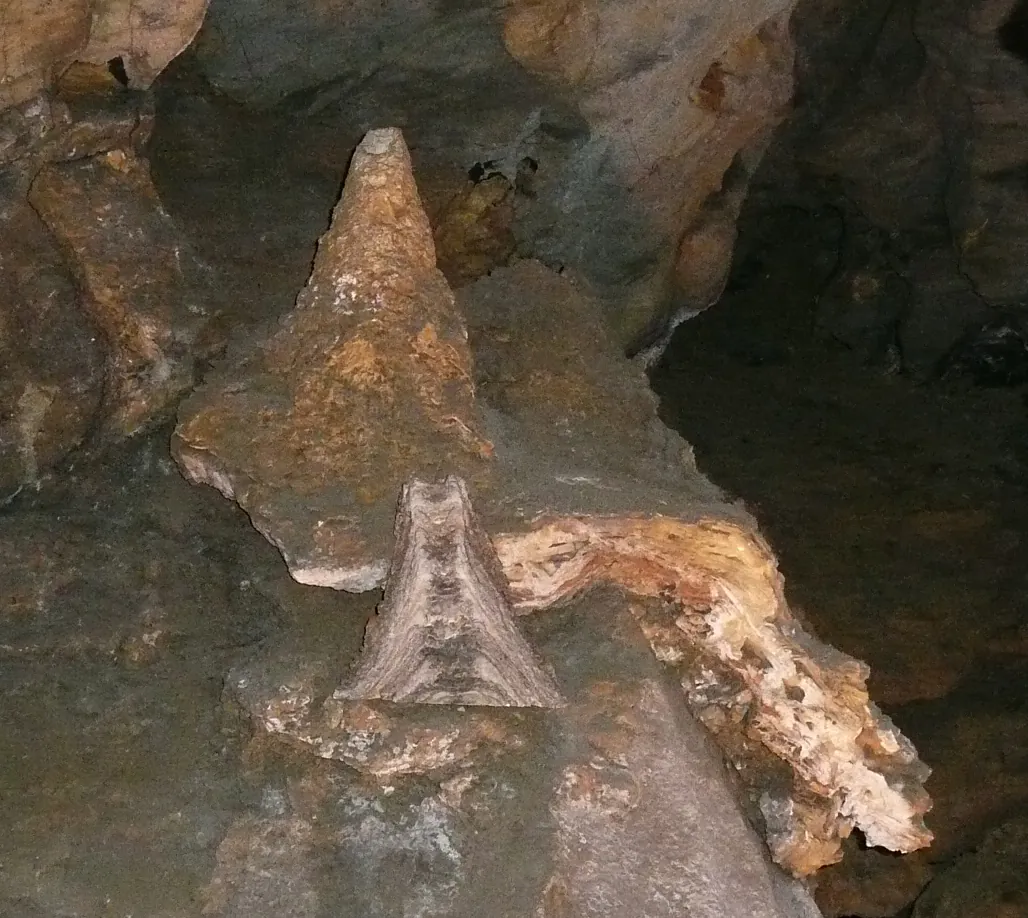 Kuželovitý gejzírový stalagmit na dně jeskynní chodby