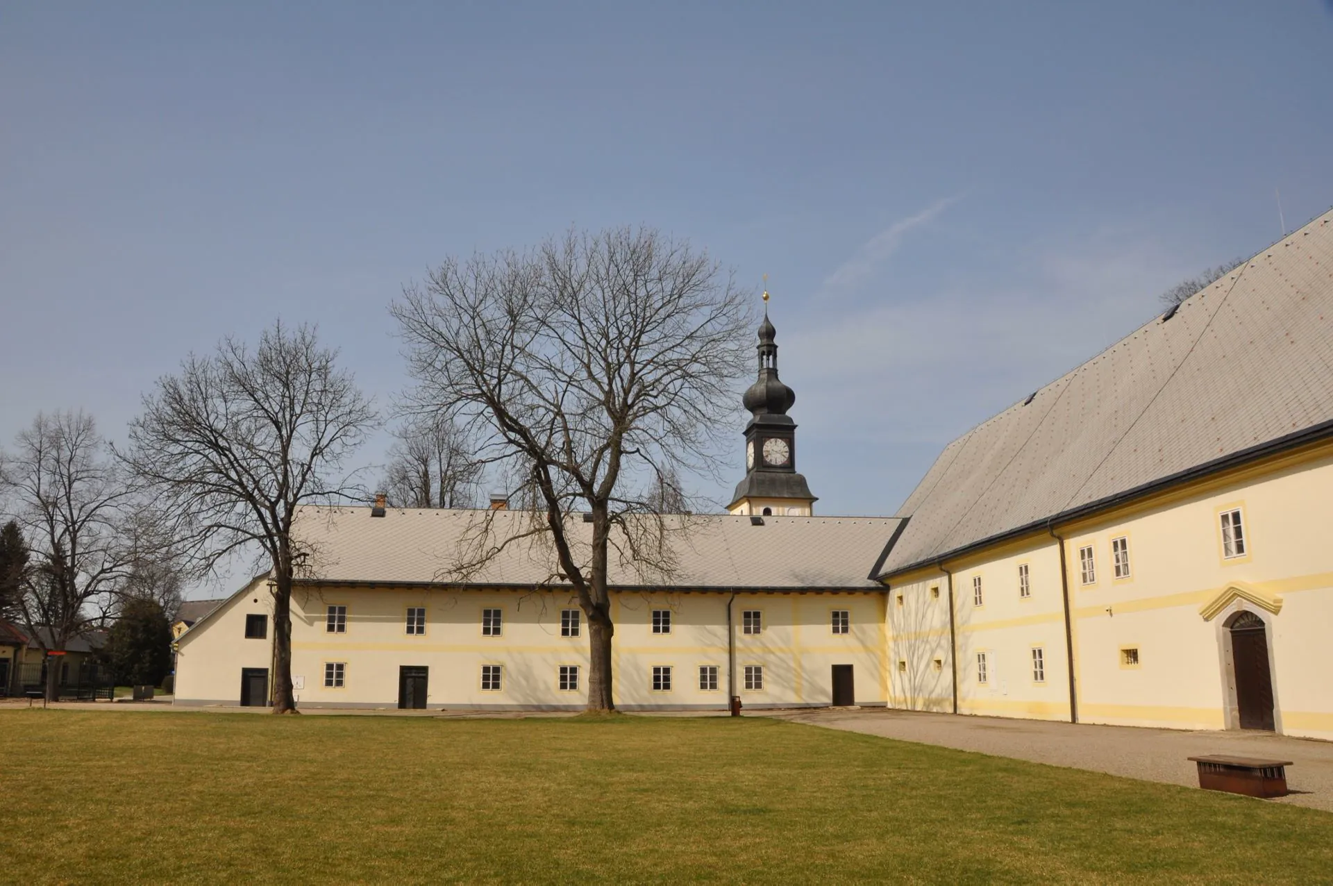 Nádvoří zámeckého areálu s věží kostela a hospodářskými budovami