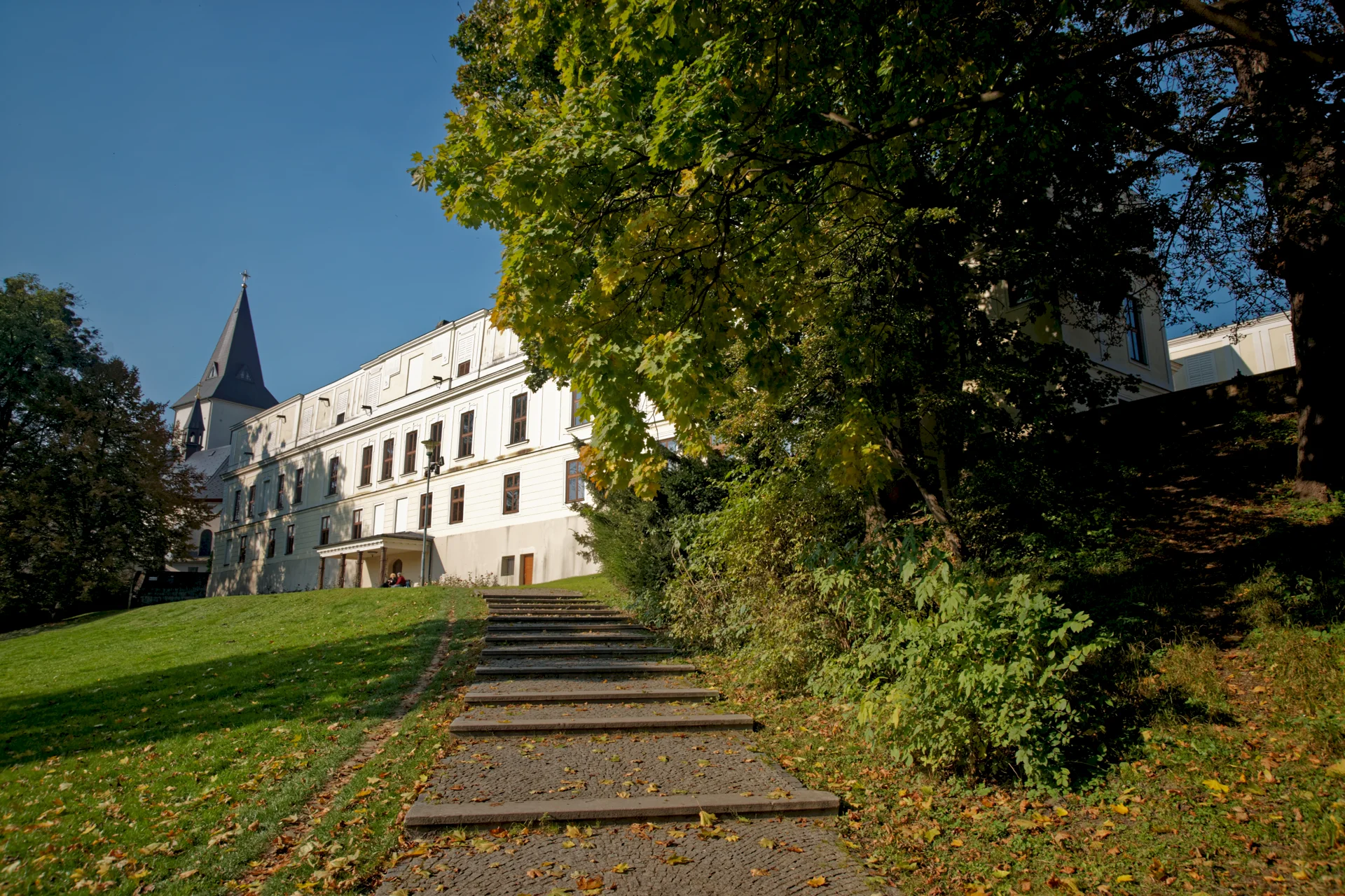 Zámek Fryštát s věží nad schodištěm v parku Boženy Němcové, kolem vzrostlé stromy