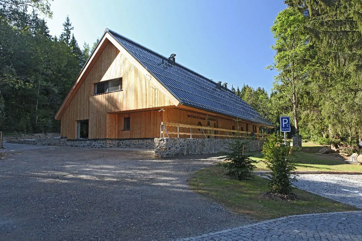 Dřevěná budova návštěvnického centra Srní s parkovištěm