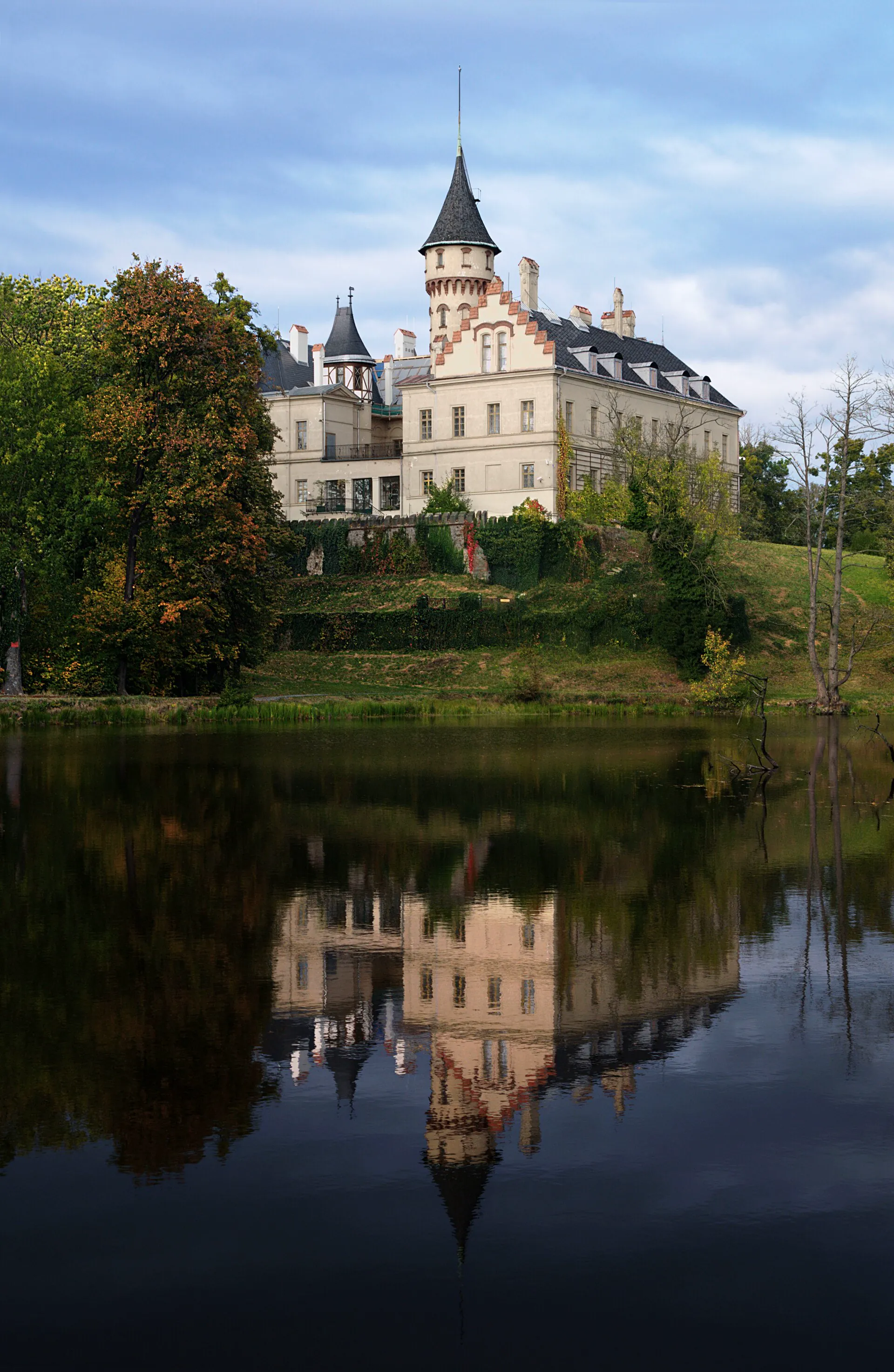 Zámecká věž zrcadlící se v hladině rybníka